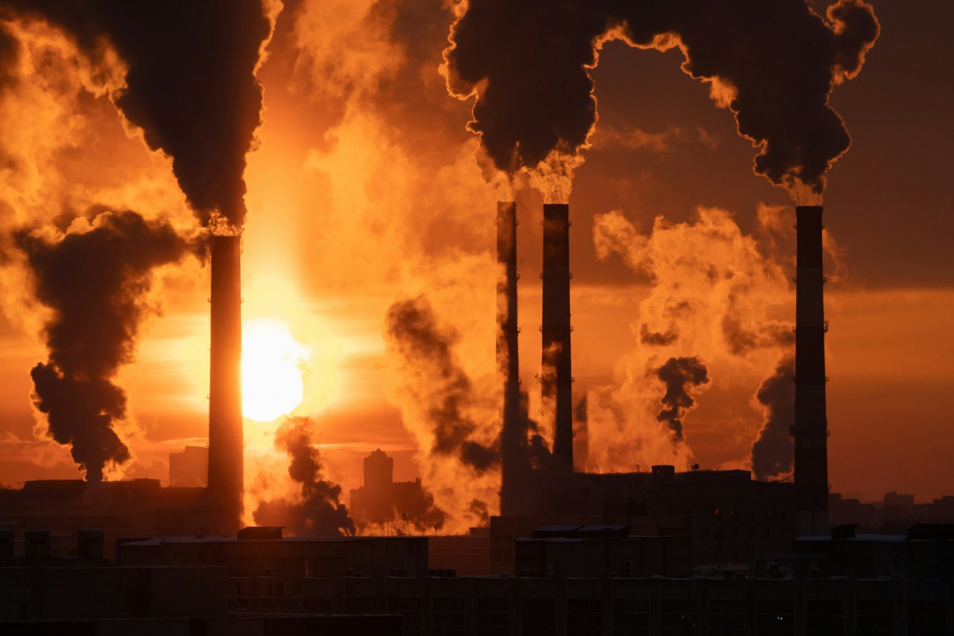 Air pollution and global warming. Smoking chimneys of thermal power plant at sunset in winter city