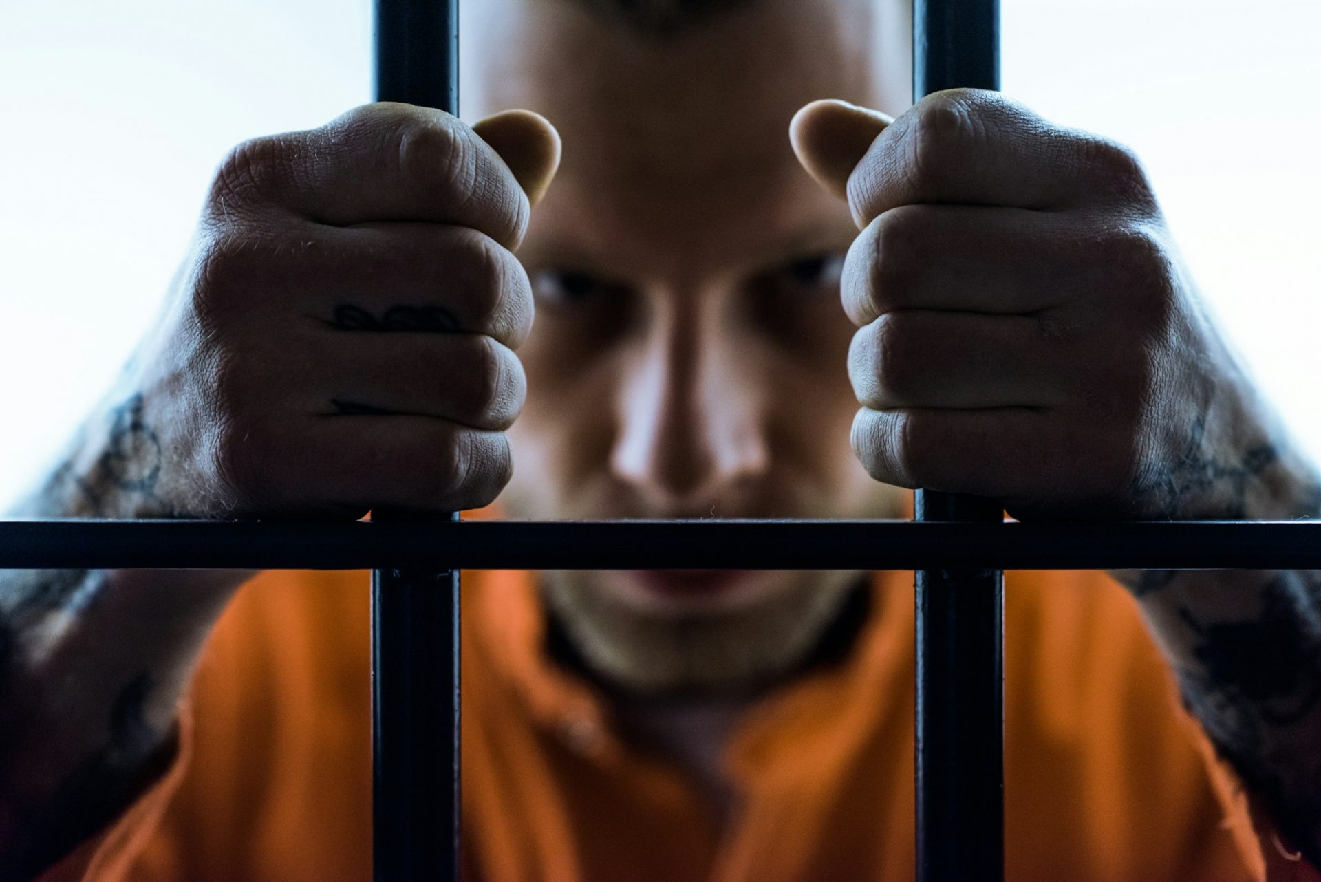 angry prisoner holding prison bars and looking at camera