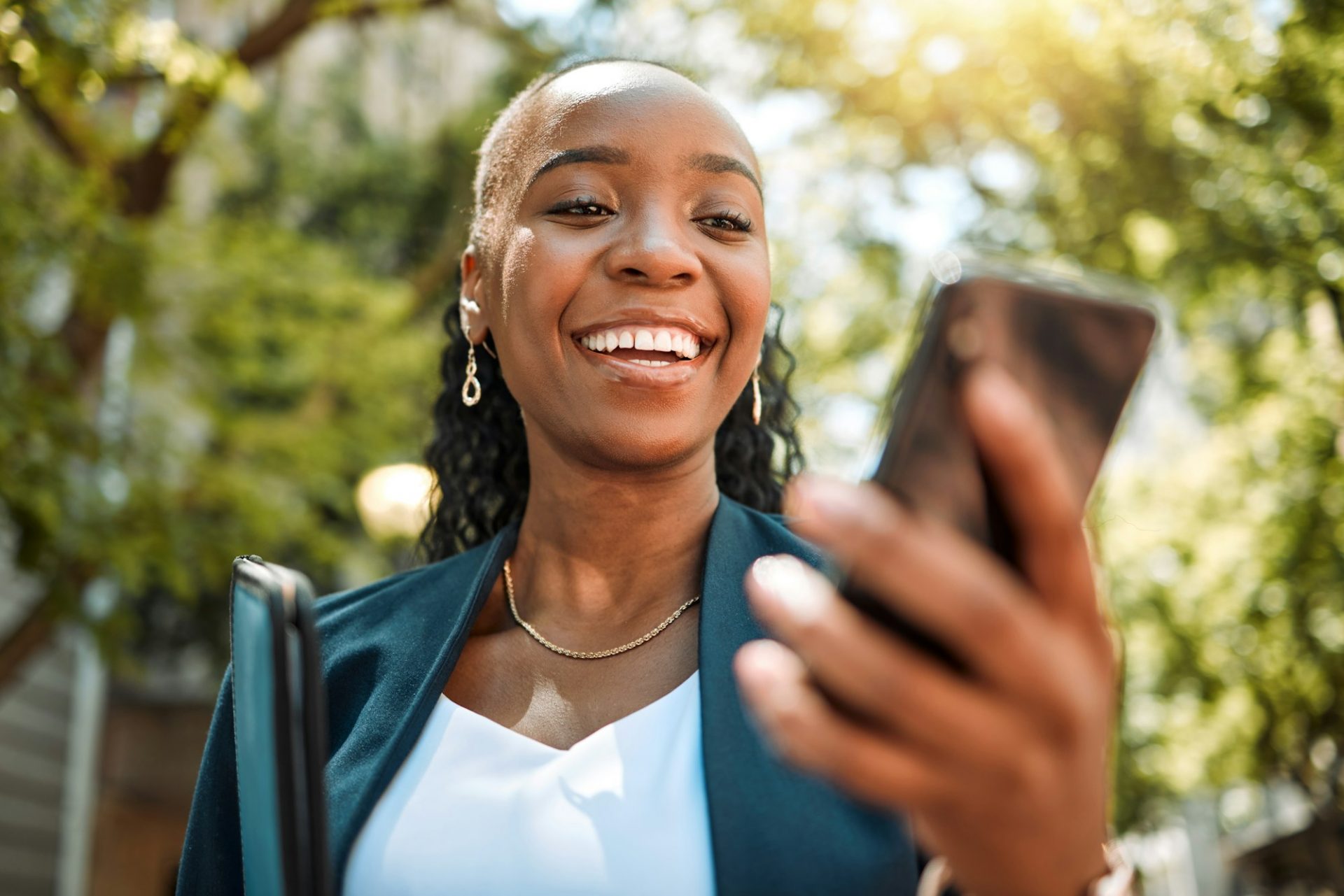 Happy black woman, phone and city for social media, communication or online browsing at the park. A