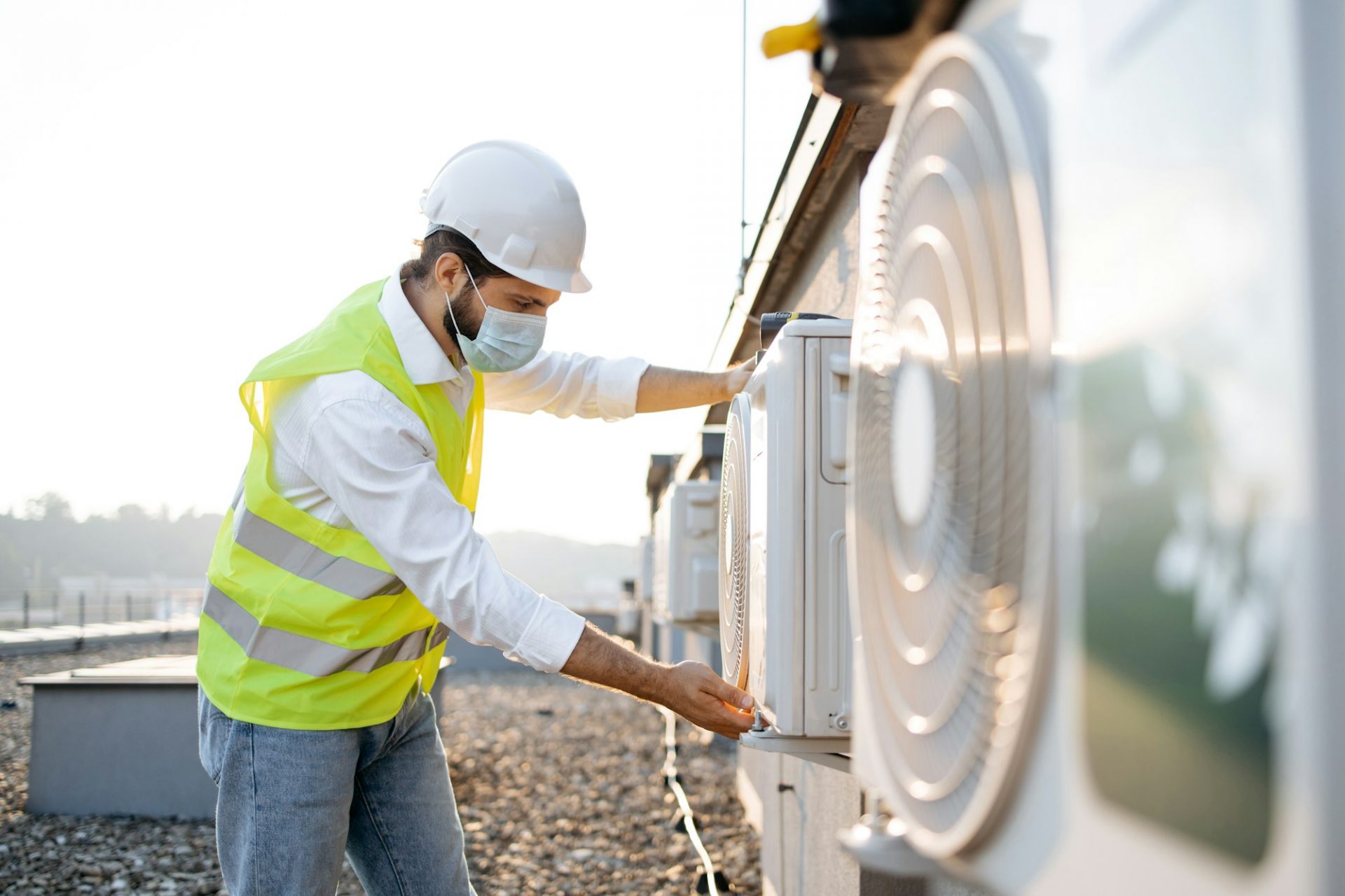 Man engineer in mask checking conditioner for serviceability