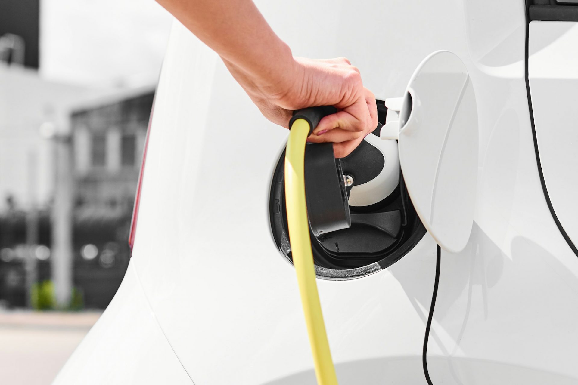 Woman unplugging a charger from an electric car socket. Eco friendly vehicle with zero emission